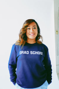 Model standing wearing the unisex slim fit eco-fleece Grad School sweatshirt in navy blue