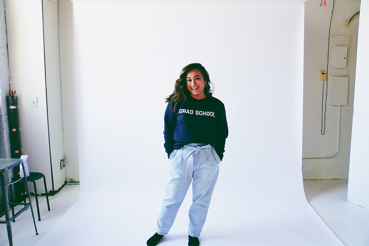 Model standing wearing the unisex slim fit eco-fleece Grad School sweatshirt in navy blue