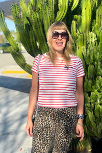 Person standing by a cactus wearing The Stripes t-shirt in white and red