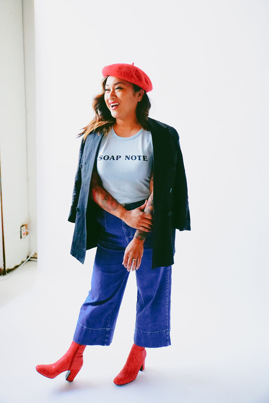 Model wearing a beret and coat with the Soap Note T-shirt in light blue