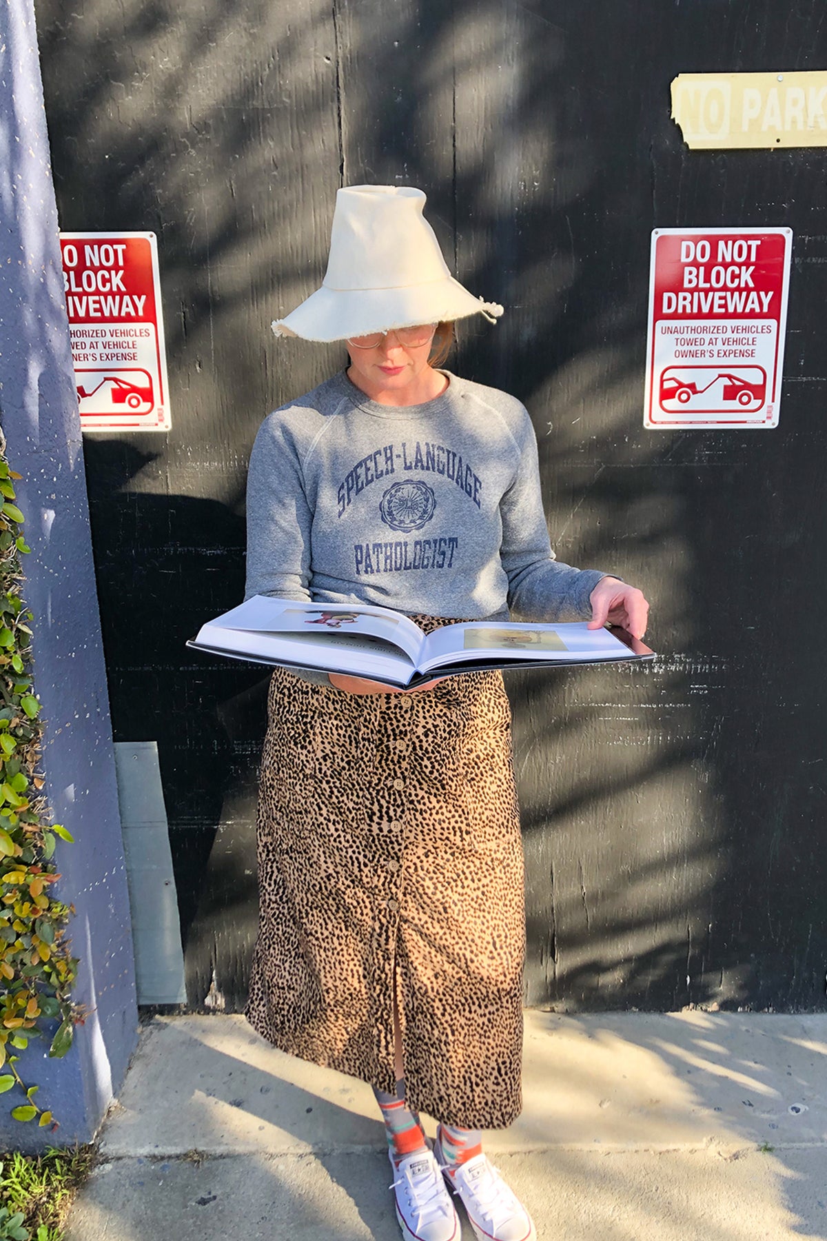 Person outside with a hat reading a book and wearing the soft slim-fit unisex Speech-Language Pathologist UNI sweatshirt in grey